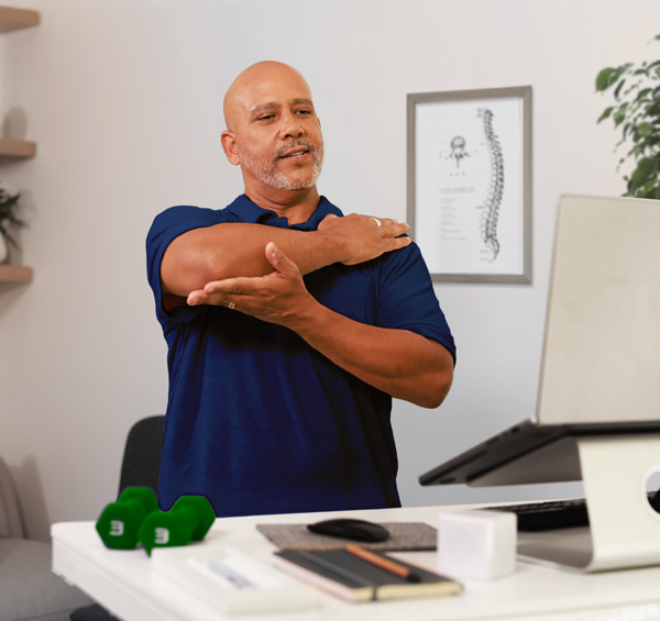 man showing arm movement in front of laptop